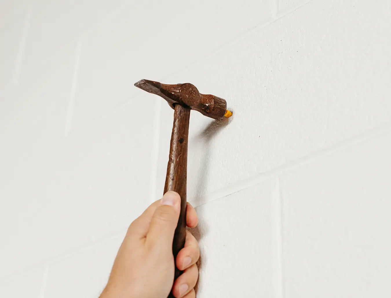 Person inserting wall anchor into drilled hole in wall.