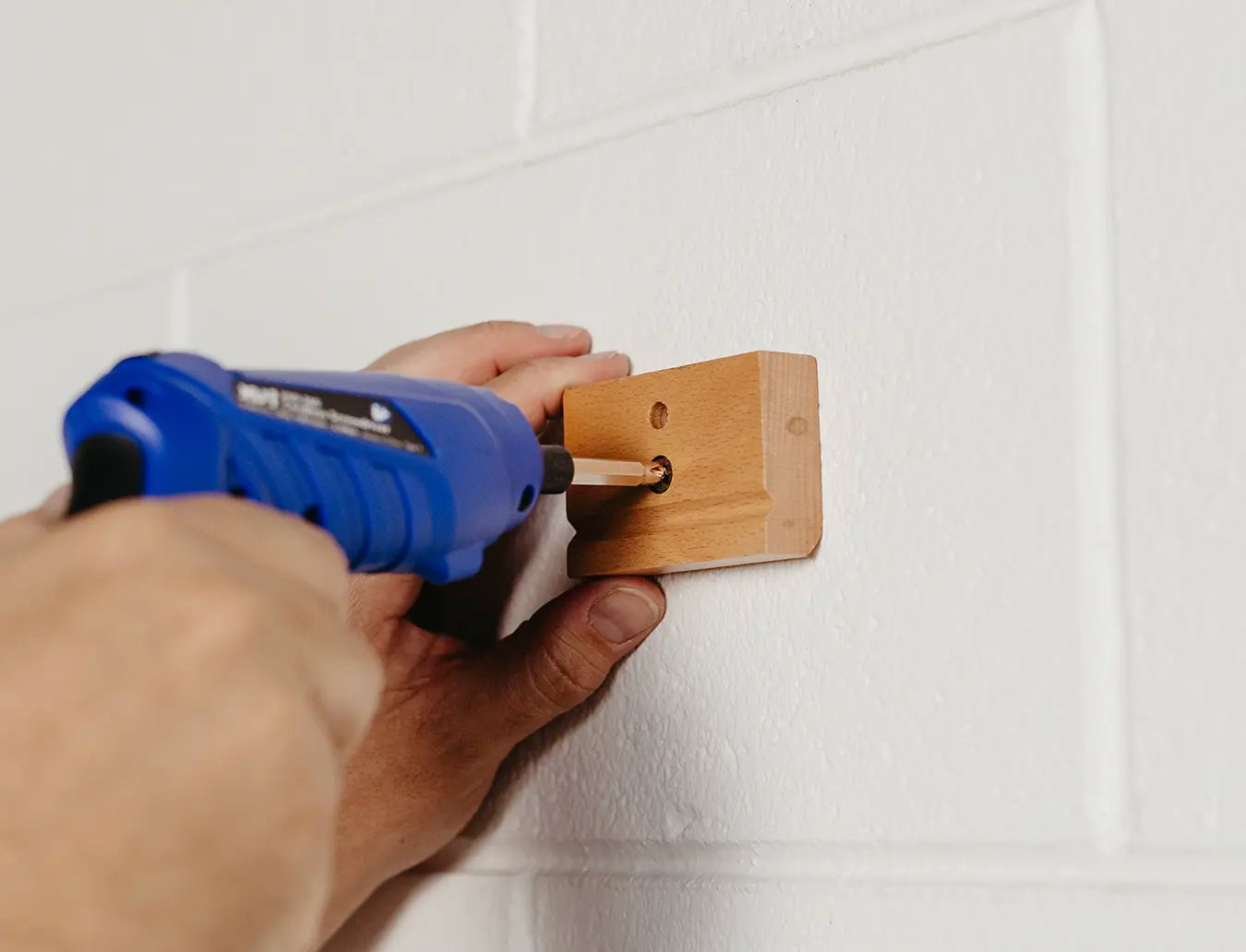 Person mounting wooden block of blanket hanger clip with a screw.