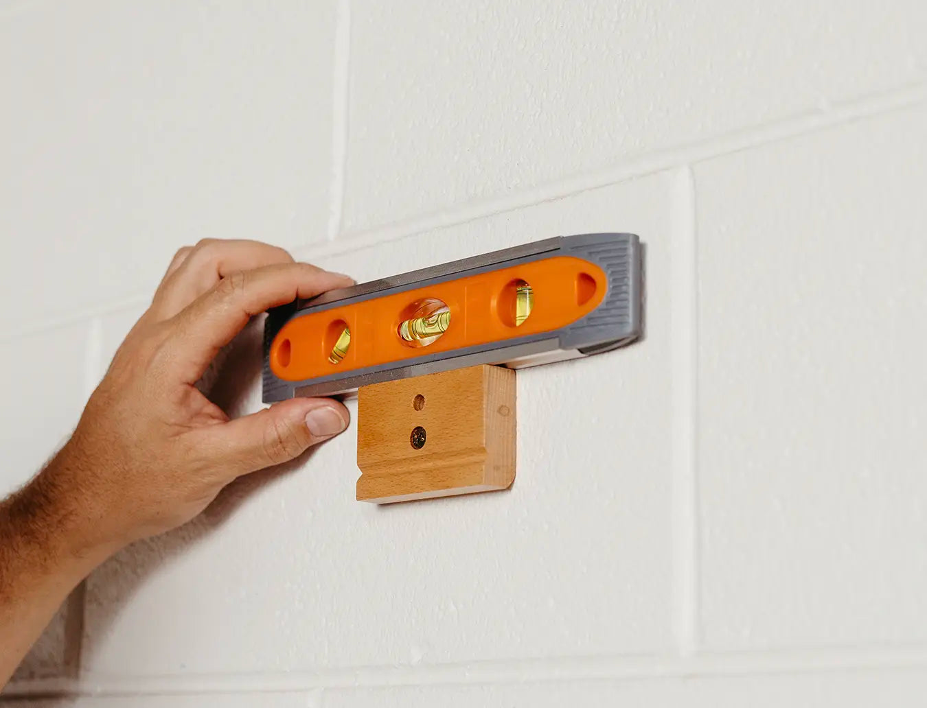 Person using spirit level to ensure the blanket hanger clip is level.