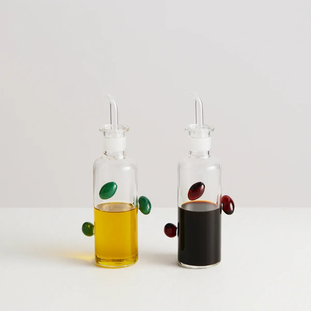 Two glass oil and vinegar bottles with droppers on a light gray background
