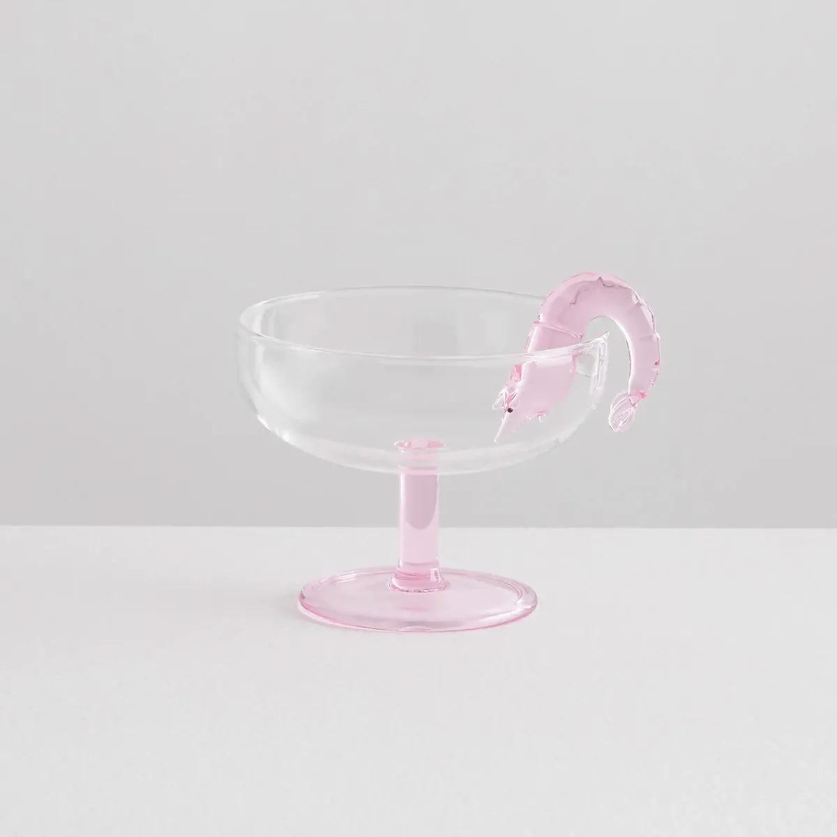 Clear glass with pink base and prawn-shaped decoration on a light gray background