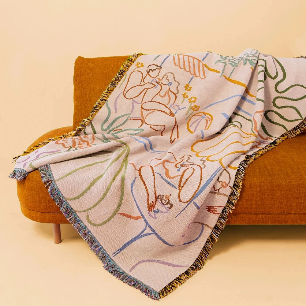 Decorative blanket with artistic design on a brown couch against a beige background