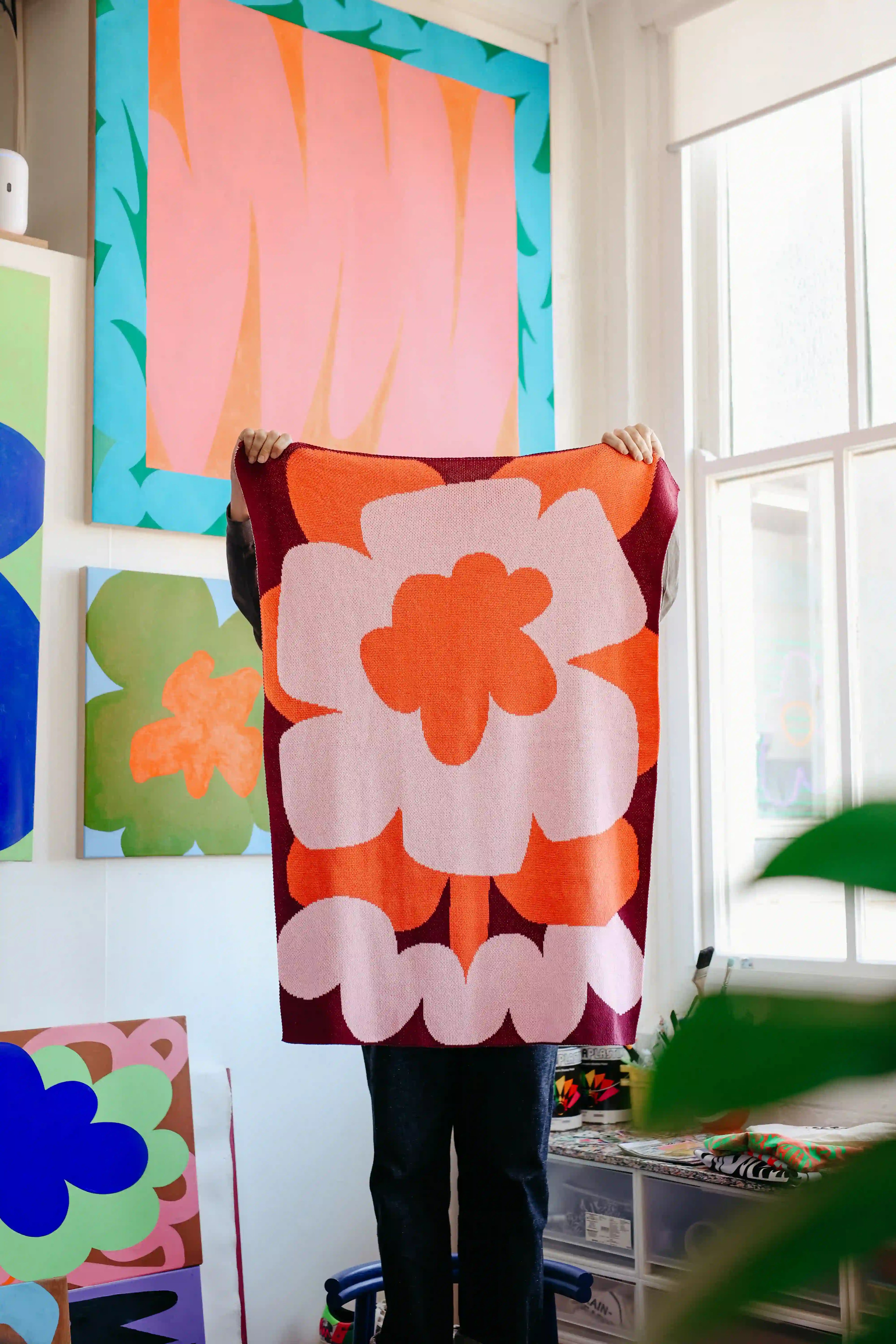 Person holding a colorful floral towel in a room with art on the wall