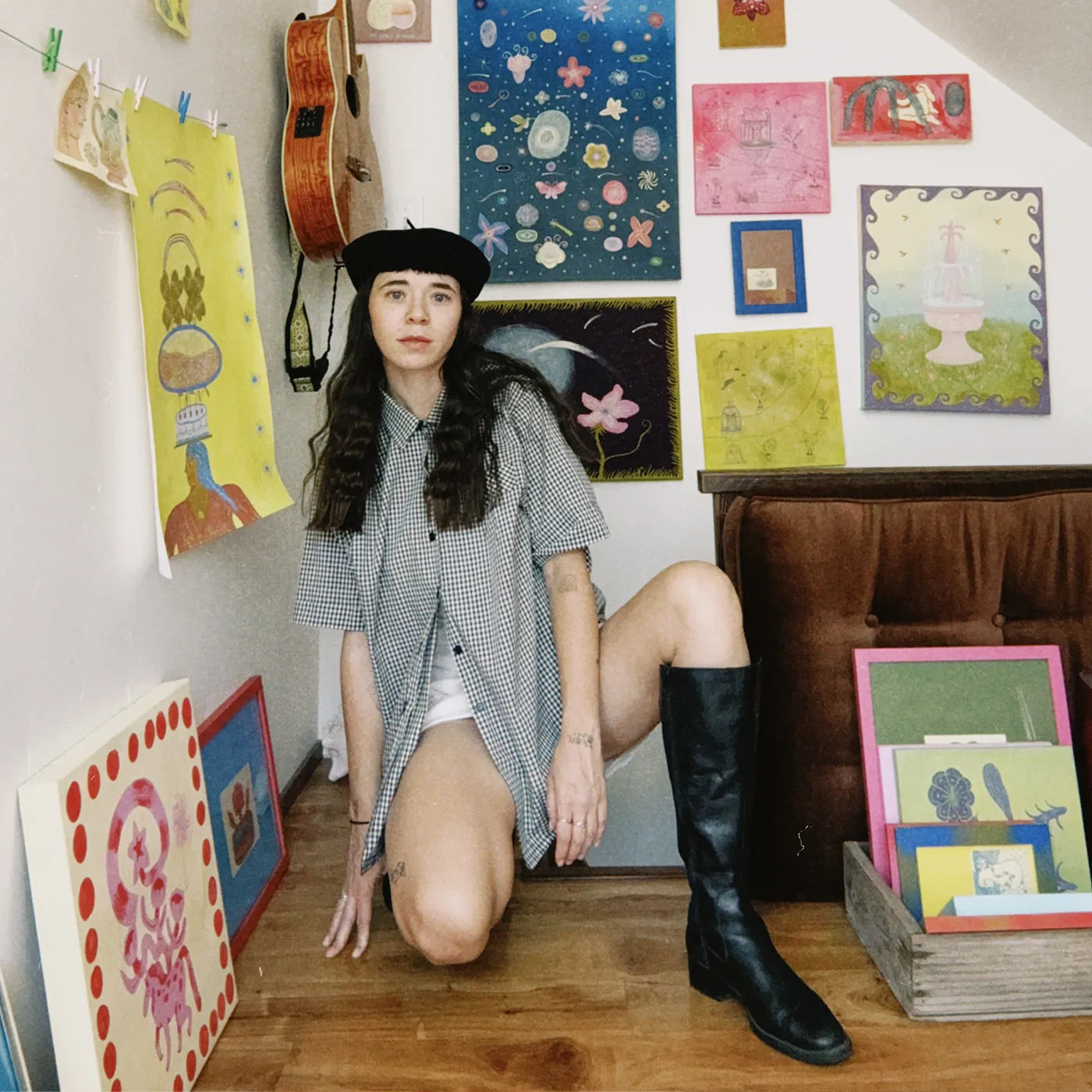 Portrait of American artist Danielle Peterson in her art studio in front of a wall of art