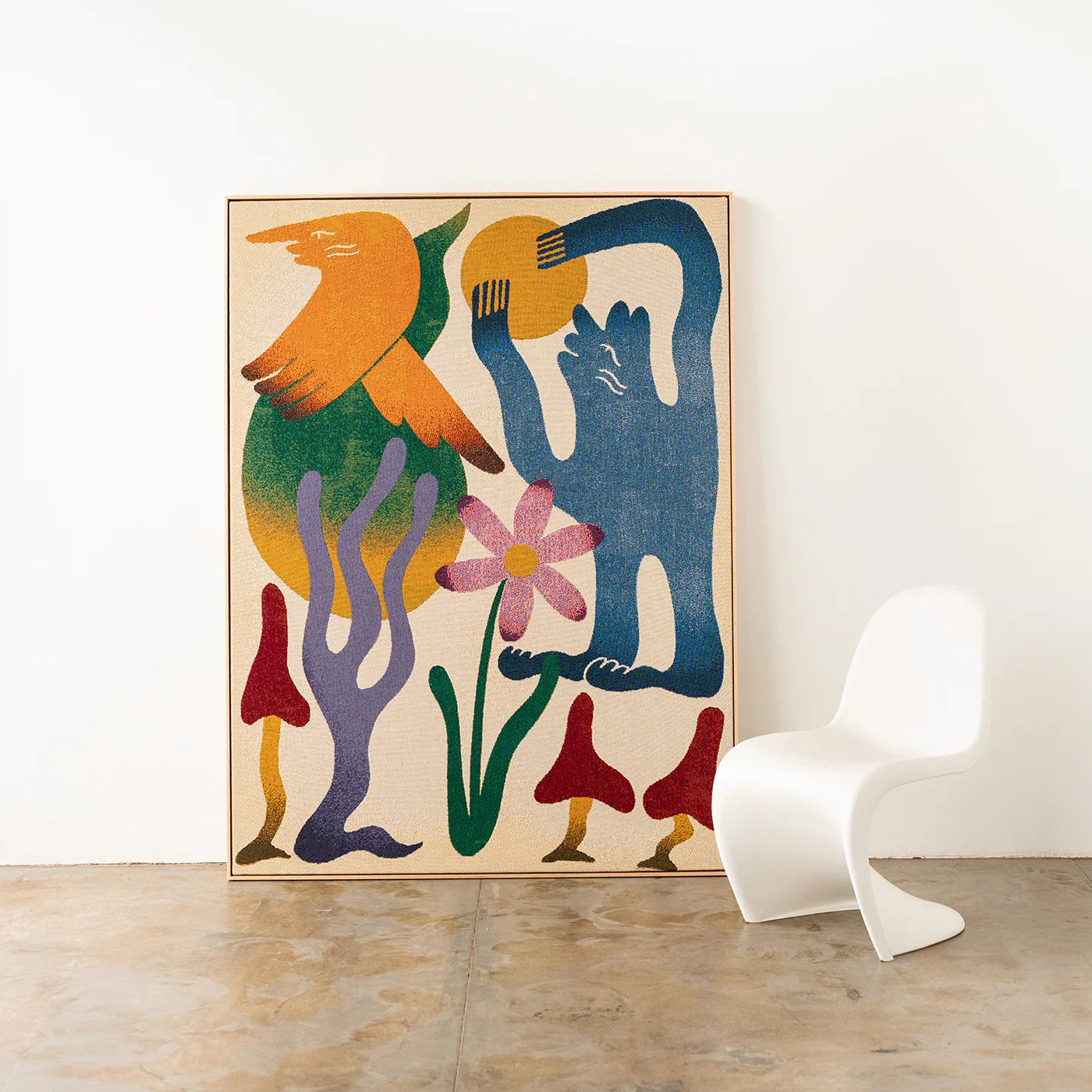 Colorful abstract artist-designed woven throw framed with an oak timber frame on a white wall with a modern curvy white chair.