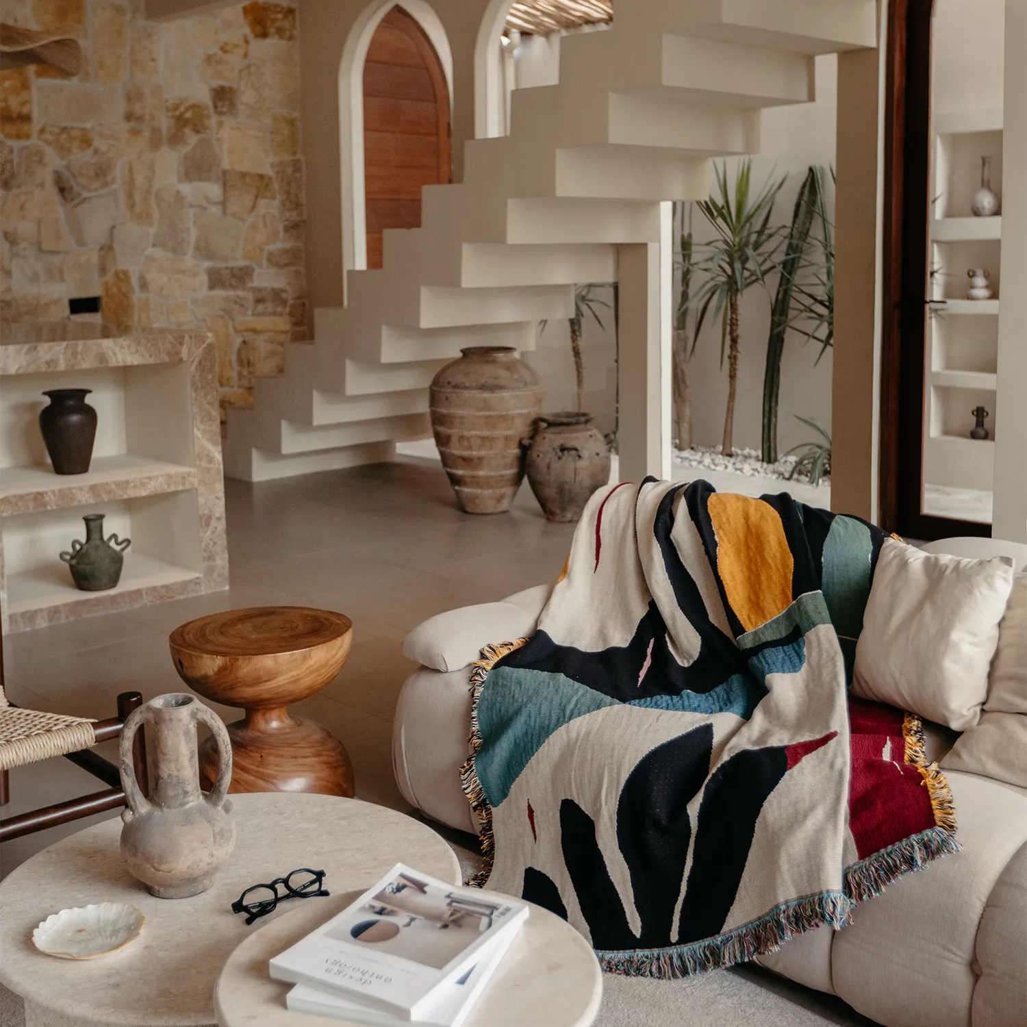 Living room with a colorful blanket draped over a sofa, stone wall, and wooden coffee table.