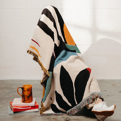 Colorful patterned blanket draped over a person sitting on the floor.