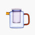 Clear blue glass tea pot with orange handle and spout on a white background