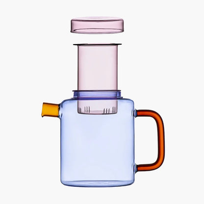 Blue glass teapot with orange handle and spout and pink diffuser and lid on a white background