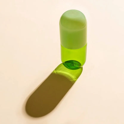 Green glass bottle with green bottle cap  on a beige background