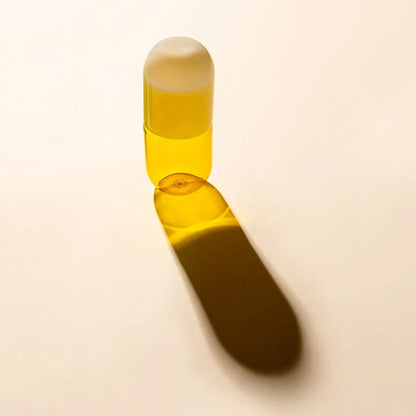 Yellow glass bottle with beige lid on a beige background