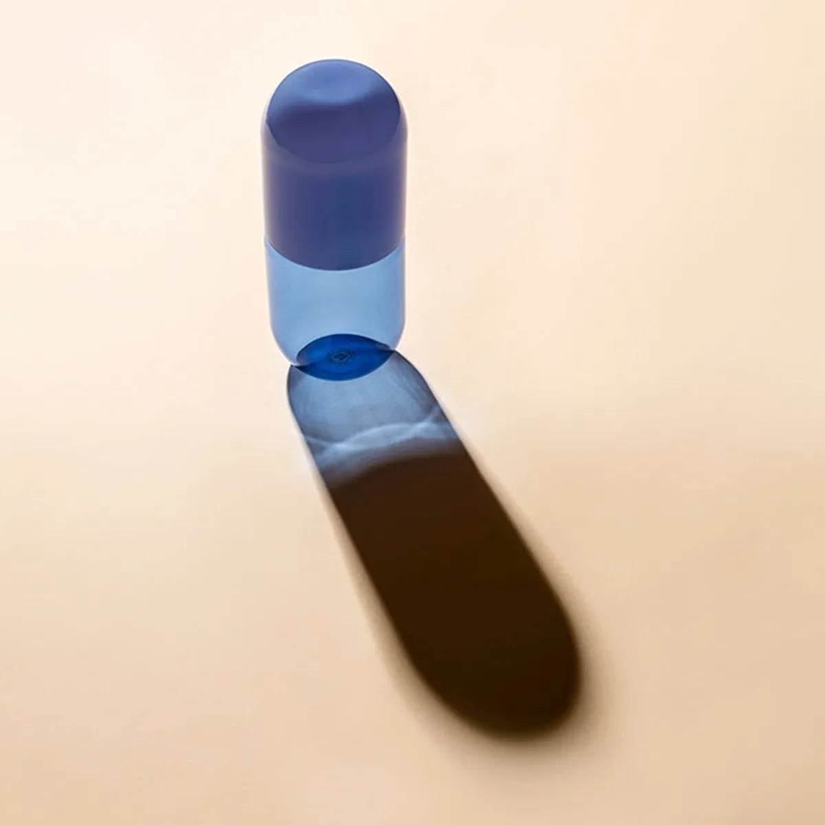Blue cylindrical bottle on a beige background