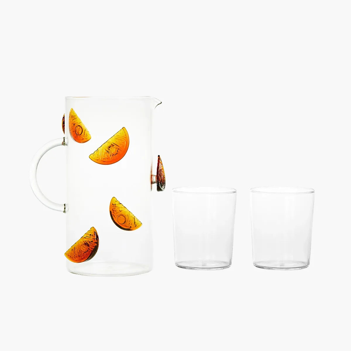 Clear glass pitcher and two glasses with orange slice design on a white background