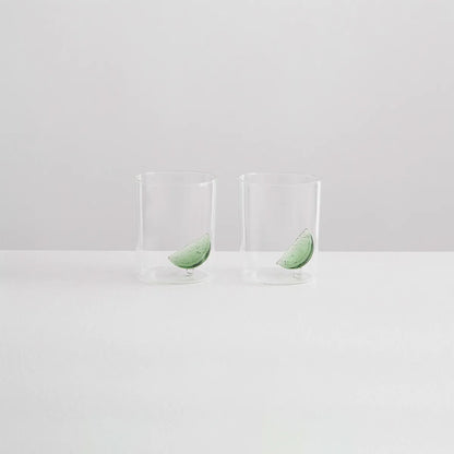 Two clear glasses with green leaves on a white background