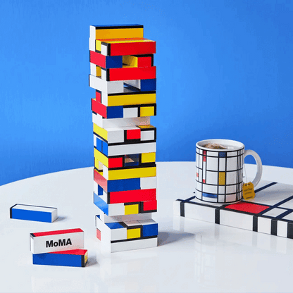 Looping video of a colorful geometric block tower and a matching mug and notebook on a white table in front of a blue background