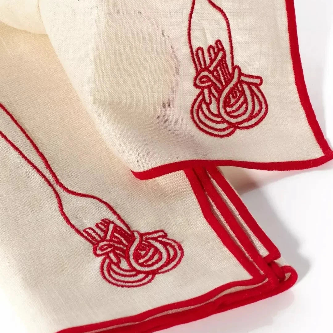 White napkin with embroidered spaghetti design on a white background