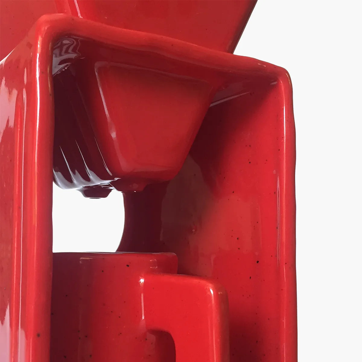 Red coffee maker pouring coffee into a red cup on a gray background