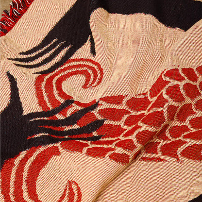 Close-up of a knit blanket fabric with red, black, and beige abstract patterns.