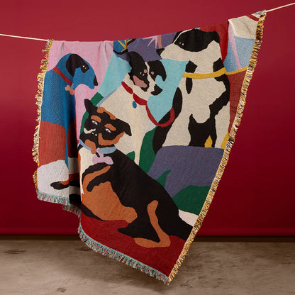 Colorful blanket with dog illustrations hanging against a red wall.