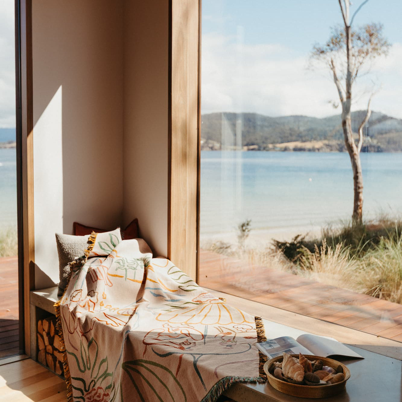 Modern interior with large windows overlooking a scenic lake and mountains.
