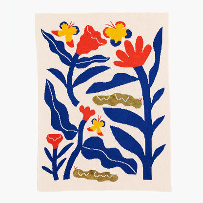 Decorative baby blanket with colorful floral and butterfly design on a beige background