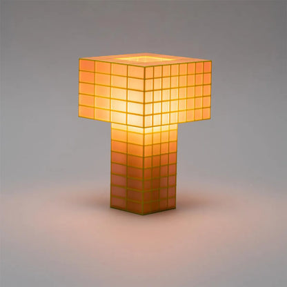 A Ridezign Tesser 5:8 table lamp with a glowing orange and yellow geometric grid design, set against a neutral gray background.
