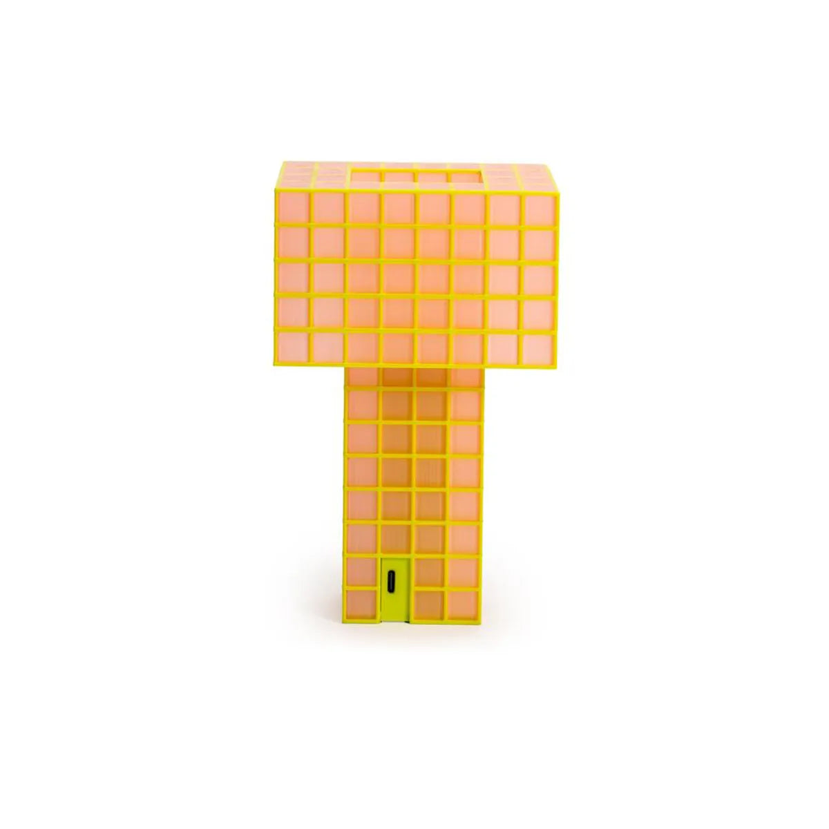 A Ridezign Tesser 5:8 Lamp with a grid pattern, featuring a bright yellow-orange body, a glowing warm pink-orange light panel on the top block, and a small lime green door at the base, set against a plain white background.