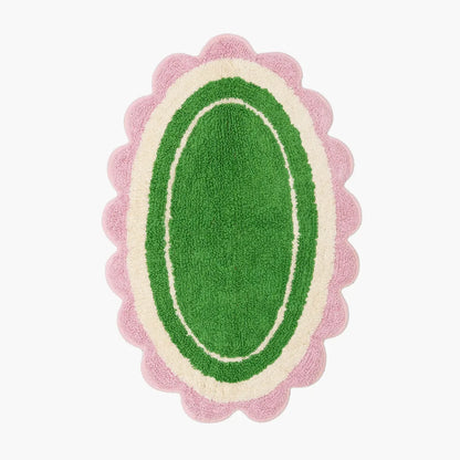 Green oval rug with pink scalloped edge on a white background