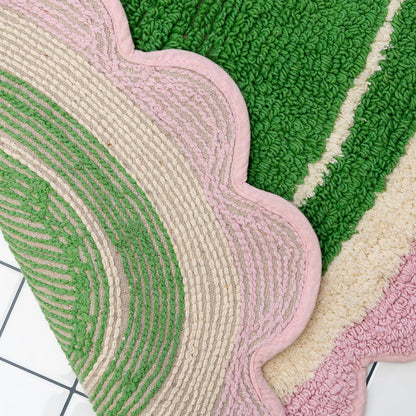 Textured bath mat in green, pink, and beige on a white background