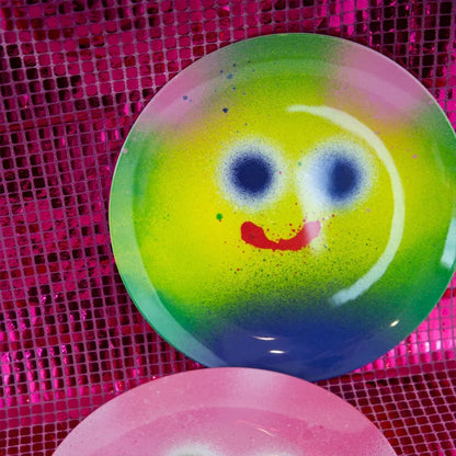 Colorful smiley face plate on a pink textured background