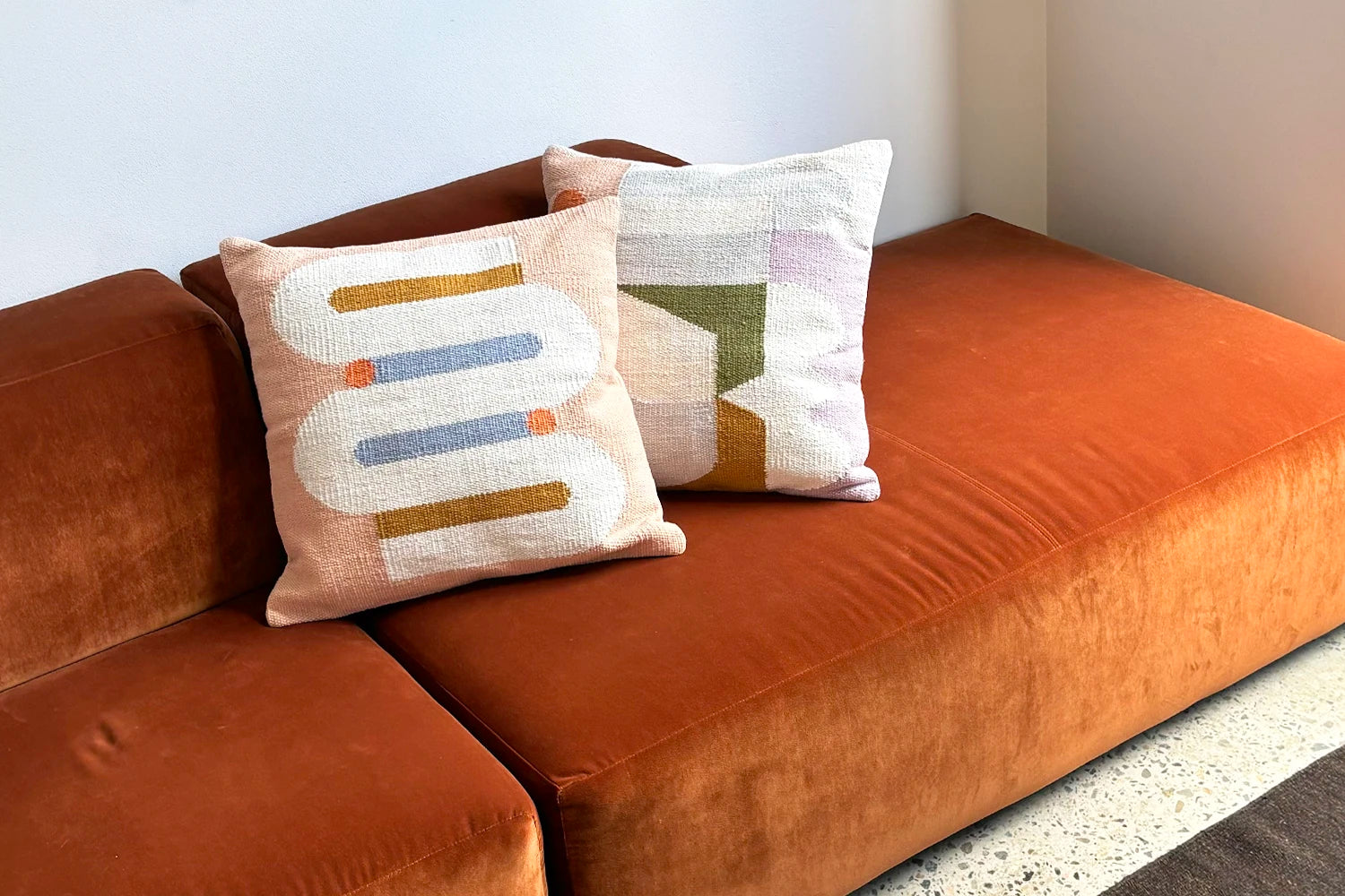 Brown sofa with patterned cushions against a neutral wall