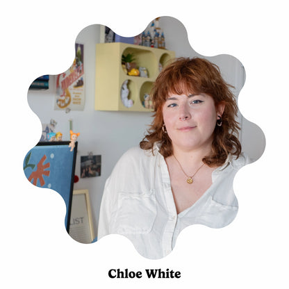 Woman with red hair wearing a white shirt, with a decorative background.